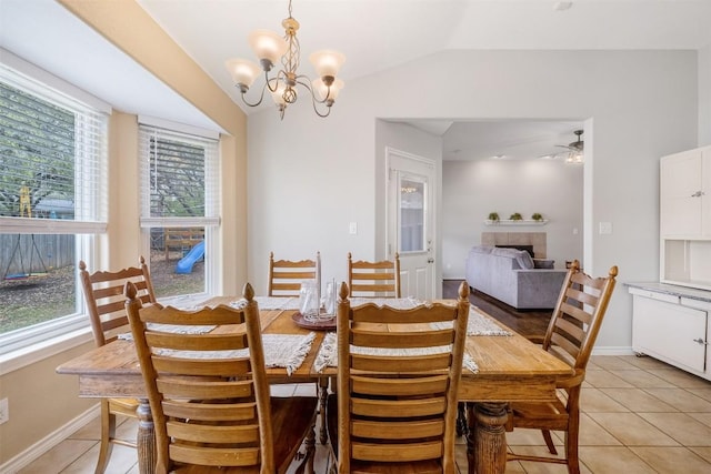 dining room with lofted ceiling, a tile fireplace, baseboards, and light tile patterned floors