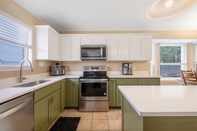 kitchen with light countertops, appliances with stainless steel finishes, green cabinetry, and a sink