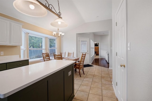 kitchen featuring light tile patterned flooring, white cabinetry, light countertops, lofted ceiling, and a notable chandelier