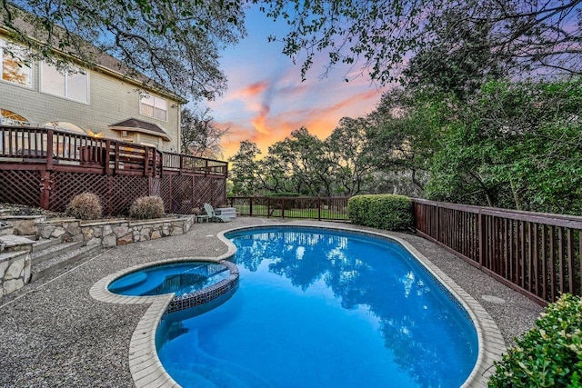 8001 Bell Mountain Dr, Austin, TX 78730 - pool at dusk featuring a wooden deck, a fenced backyard, and a pool with connected hot tub