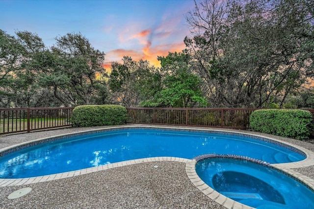 8001 Bell Mountain Dr, Austin, TX 78730 - pool at dusk featuring a fenced backyard, a pool with connected hot tub, and view of scattered trees
