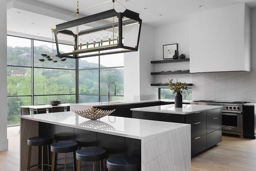 2701 Toro Canyon Rd Unit B, Austin, TX 78746 - kitchen with a center island, stainless steel stove, modern cabinets, light wood-type flooring, and expansive windows