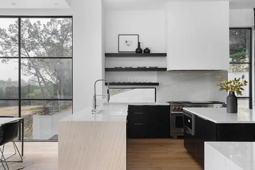 2701 Toro Canyon Rd Unit B, Austin, TX 78746 - kitchen with stainless steel stove, dark cabinetry, light countertops, light wood finished floors, and decorative backsplash