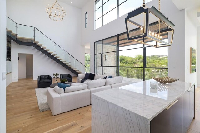 2701 Toro Canyon Rd Unit B, Austin, TX 78746 - living area with a chandelier, light wood-style flooring, stairway, a high ceiling, and healthy amount of natural light