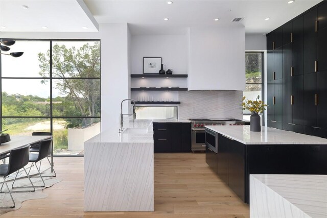 2701 Toro Canyon Rd Unit B, Austin, TX 78746 - kitchen featuring dark cabinetry, modern cabinets, high end stainless steel range oven, recessed lighting, and expansive windows