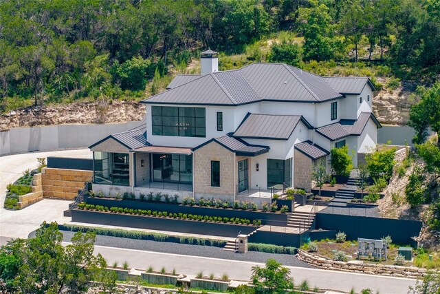 2701 Toro Canyon Rd Unit B, Austin, TX 78746 - view of front of house featuring a standing seam roof, a metal roof, a chimney, and a view of trees