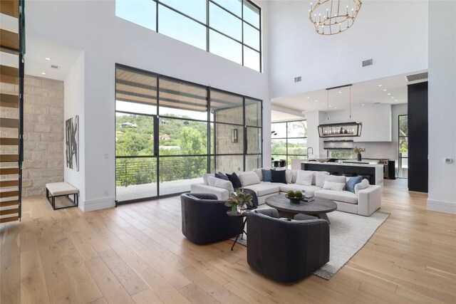 2701 Toro Canyon Rd Unit B, Austin, TX 78746 - living area featuring a chandelier, a towering ceiling, light wood-style floors, and healthy amount of natural light