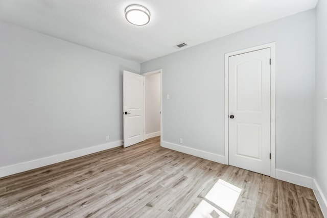 unfurnished bedroom featuring baseboards, light wood-style floors, and visible vents