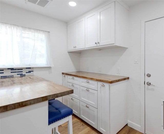 12300 Cassady Dr, Austin, TX 78727 - kitchen featuring butcher block countertops, light wood-type flooring, white cabinetry, recessed lighting, and a kitchen bar