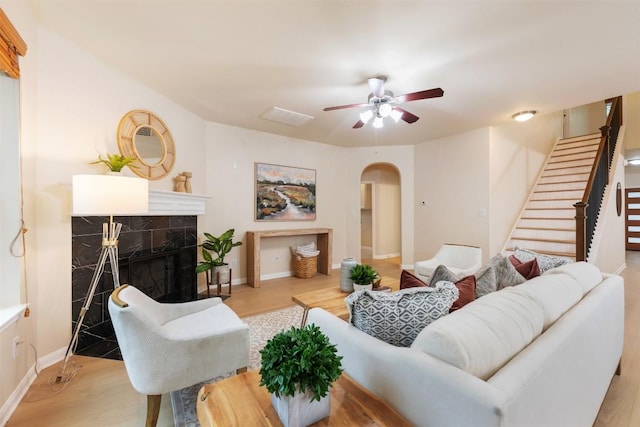3615 Turkey Path Bnd, Cedar Park, TX 78613 - living area with a ceiling fan, arched walkways, light wood-style floors, stairway, and a premium fireplace