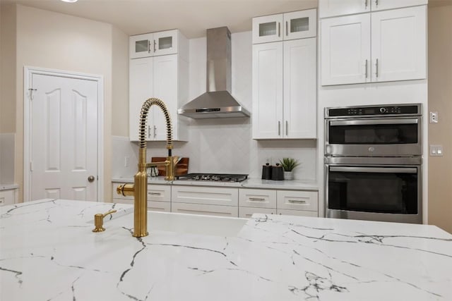 3615 Turkey Path Bnd, Cedar Park, TX 78613 - kitchen with wall chimney range hood, double oven, white cabinets, and light stone countertops