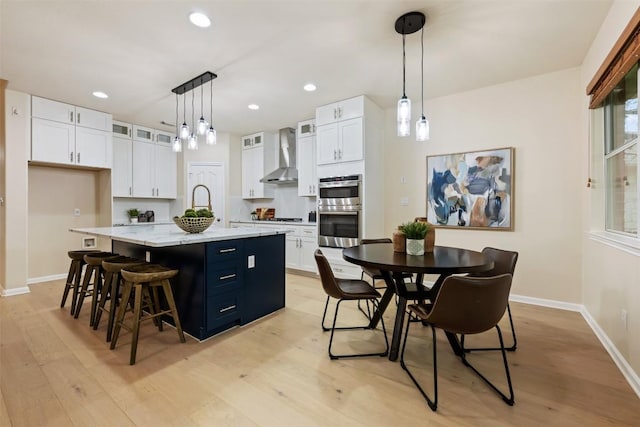 3615 Turkey Path Bnd, Cedar Park, TX 78613 - kitchen with wall chimney exhaust hood, double oven, light wood finished floors, white cabinets, and recessed lighting