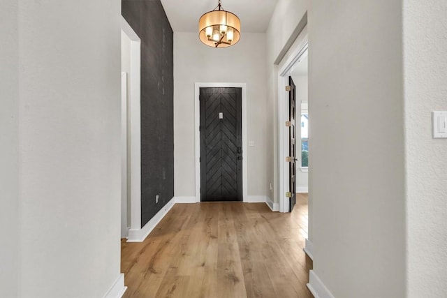 entrance foyer featuring light wood-style floors, a chandelier, and baseboards