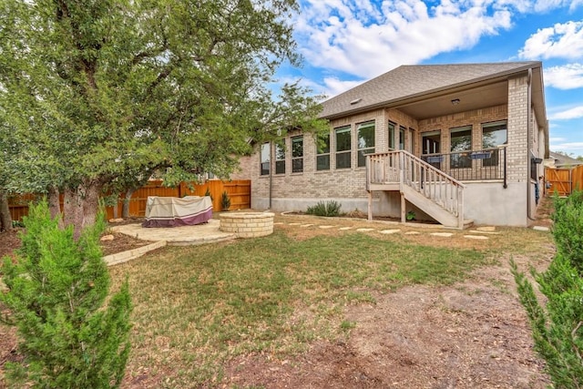 rear view of property with brick siding, an outdoor fire pit, and stairs