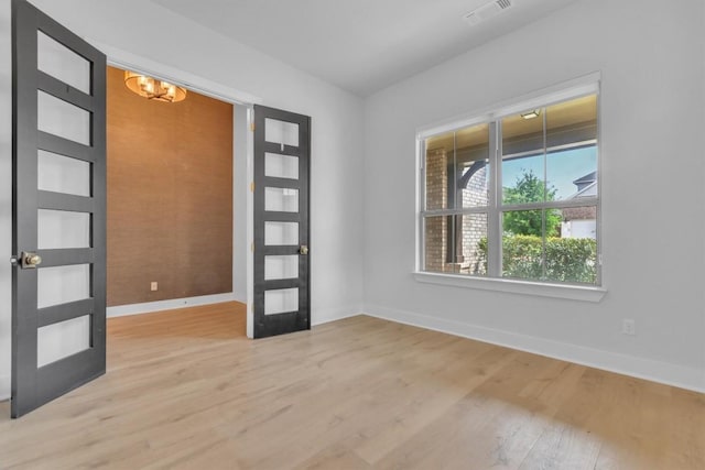 entryway featuring baseboards, light wood-type flooring, a chandelier, and french doors