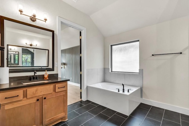 bathroom featuring lofted ceiling, vanity, a bath, tile patterned flooring, and baseboards