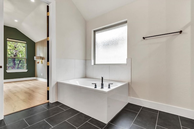 bathroom featuring vaulted ceiling, a bath, tile patterned floors, and baseboards