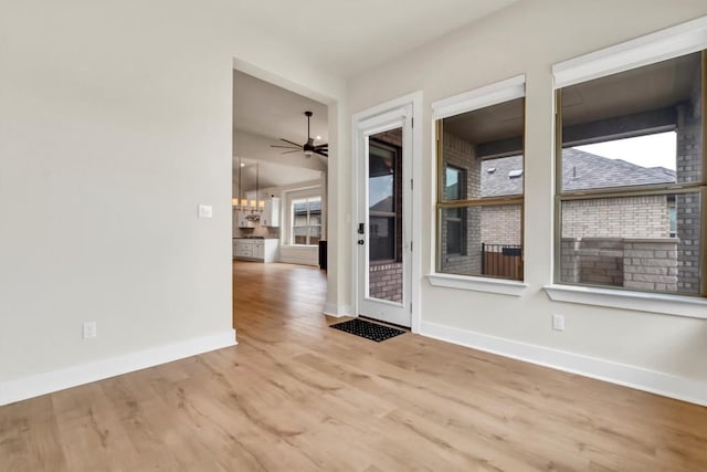 unfurnished room with baseboards, wood finished floors, and a ceiling fan