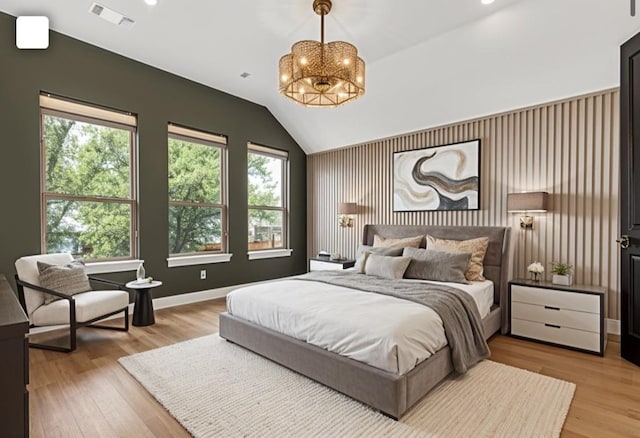 bedroom featuring a chandelier, light wood-style floors, vaulted ceiling, and baseboards