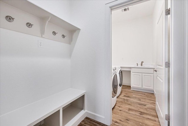 5701 Cherokee Draw Rd, Austin, TX 78738 - laundry area featuring washing machine and clothes dryer, light wood-style floors, baseboards, and cabinet space