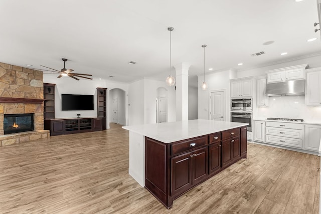5701 Cherokee Draw Rd, Austin, TX 78738 - kitchen featuring under cabinet range hood, ceiling fan, light countertops, arched walkways, and white cabinetry