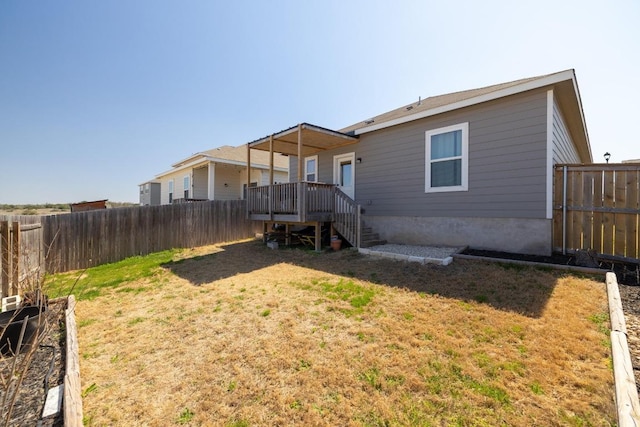 rear view of property featuring a fenced backyard and a lawn