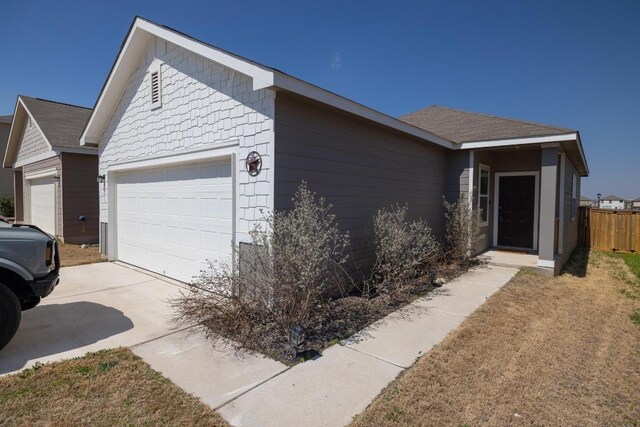 view of home's exterior featuring fence, an attached garage, and concrete driveway
