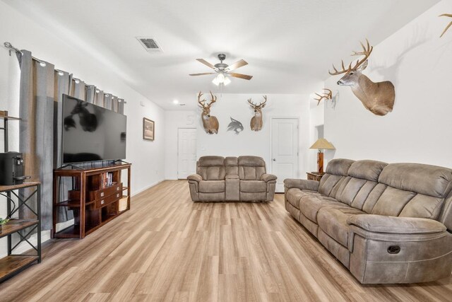 living room featuring light wood-style flooring, ceiling fan, and visible vents