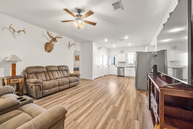 living room with baseboards, visible vents, light wood-style floors, ceiling fan, and recessed lighting