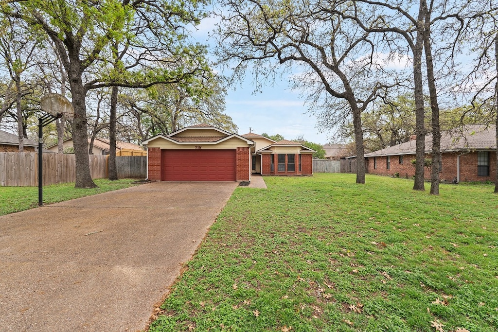 single story home featuring fence, driveway, an attached garage, and brick siding