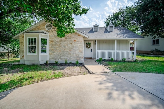 10418 Doc Holliday Trl, Austin, TX 78753 - view of front facade with stone siding, covered porch, board and batten siding, a front yard, and roof with shingles