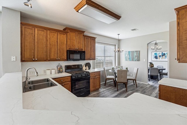 1606 Belvedere Pl, Round Rock, TX 78665 - kitchen with black appliances, a chandelier, a sink, brown cabinets, and dark wood-type flooring