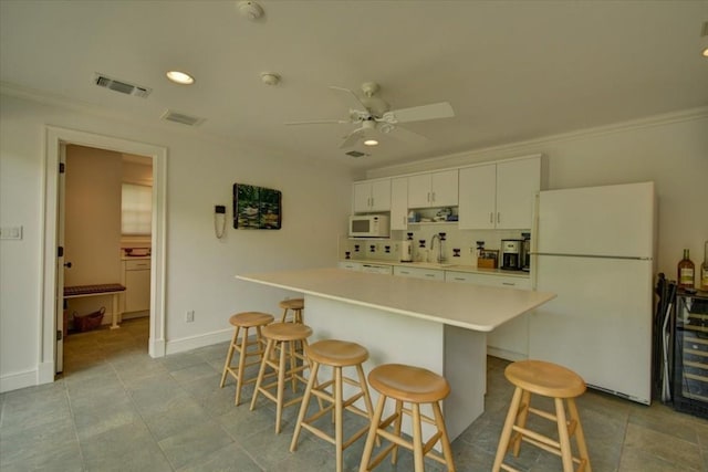 3208 Rain Dance Cv, Austin, TX 78746 - kitchen featuring white appliances, wine cooler, white cabinetry, a center island, and a breakfast bar area