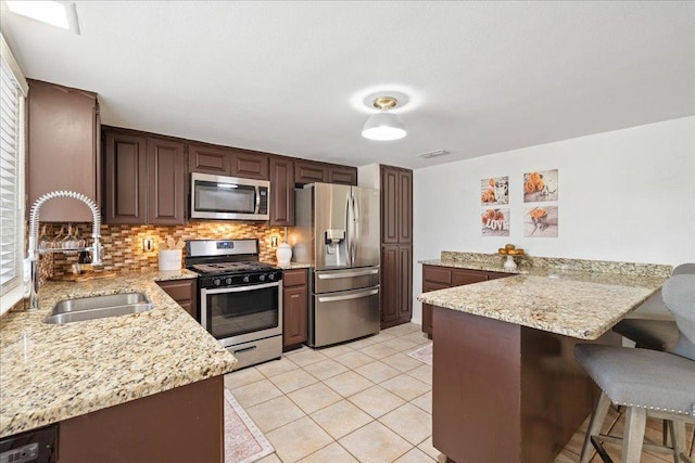 8204 Seminary Ridge Dr, Austin, TX 78745 - kitchen featuring appliances with stainless steel finishes, a peninsula, decorative backsplash, a breakfast bar, and light stone countertops