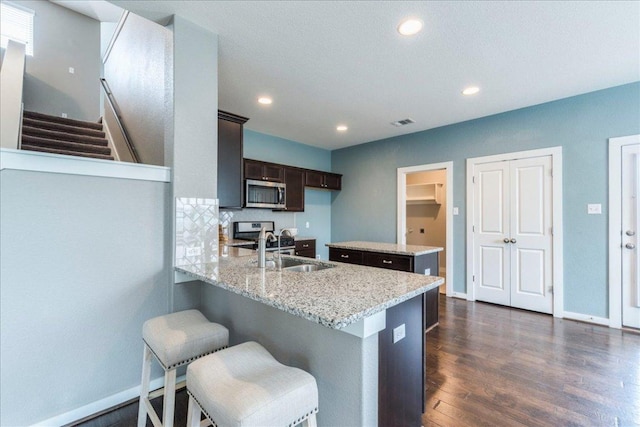 109 Pine Is, Leander, TX 78641 - kitchen featuring stainless steel microwave, a peninsula, dark wood finished floors, dark brown cabinetry, and a center island