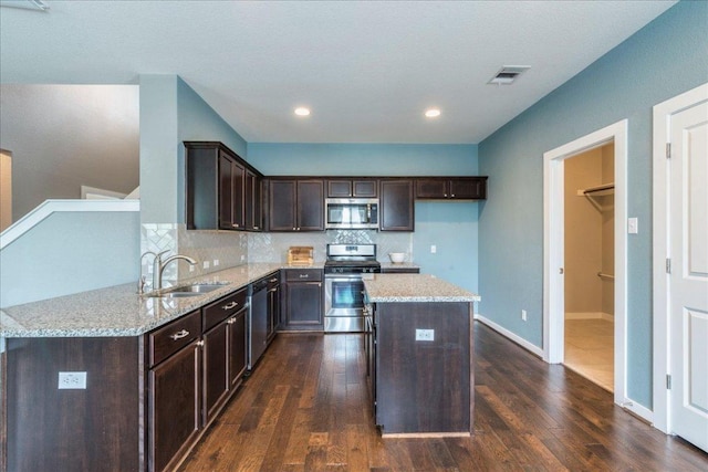 109 Pine Is, Leander, TX 78641 - kitchen with stainless steel appliances, light stone countertops, dark brown cabinets, dark wood-style flooring, and tasteful backsplash