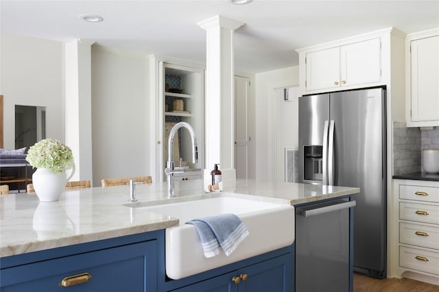 1904 Meadowbrook Dr, Austin, TX 78703 - kitchen with stainless steel appliances, a sink, decorative backsplash, light stone countertops, and blue cabinets