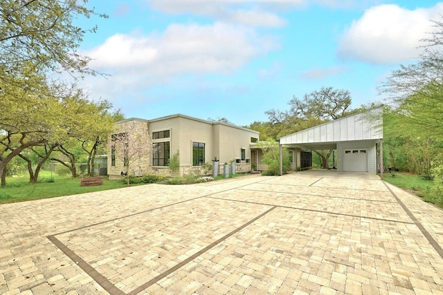 9206 Chisholm Ln, Austin, TX 78748 - view of home's exterior featuring decorative driveway, a carport, stone siding, stucco siding, and a garage