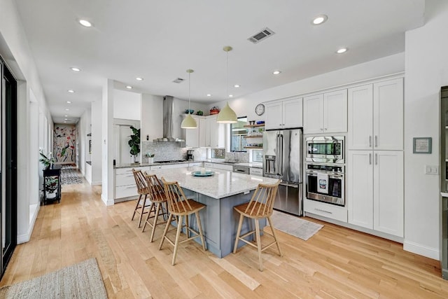 9206 Chisholm Ln, Austin, TX 78748 - kitchen with stainless steel appliances, island range hood, a kitchen island, light wood-style flooring, and decorative backsplash