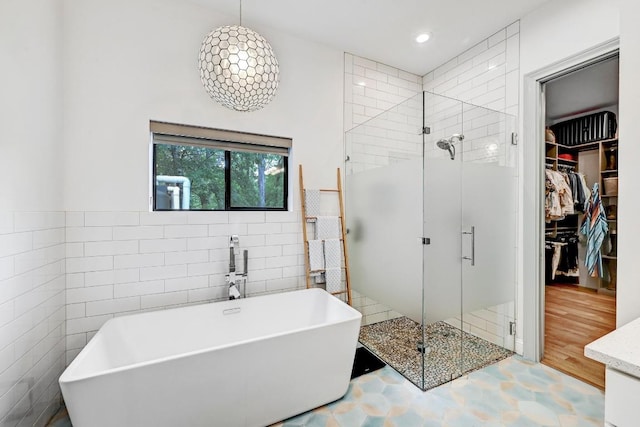 9206 Chisholm Ln, Austin, TX 78748 - bathroom featuring tile walls, a shower stall, a freestanding bath, a walk in closet, and recessed lighting