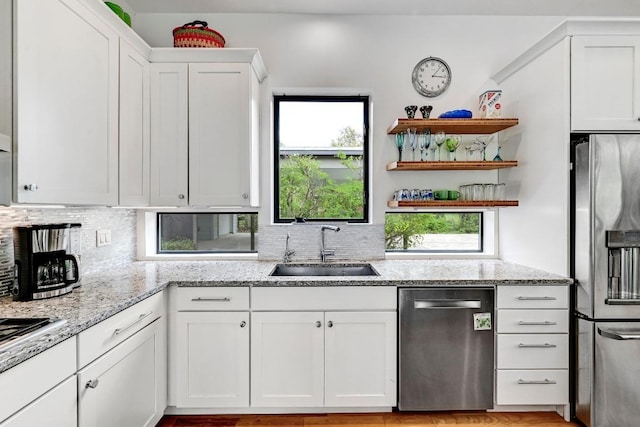 9206 Chisholm Ln, Austin, TX 78748 - kitchen with stainless steel appliances, open shelves, white cabinetry, backsplash, and light stone counters