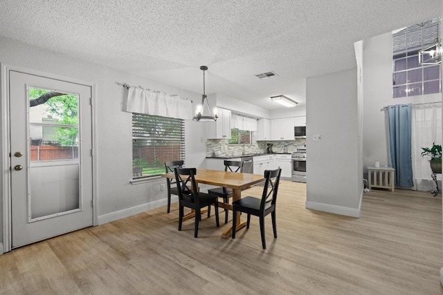 8410 Glen Canyon Dr, Round Rock, TX 78681 - dining space with a textured ceiling, light wood-style flooring, and a chandelier