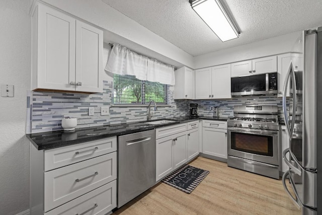 8410 Glen Canyon Dr, Round Rock, TX 78681 - kitchen with appliances with stainless steel finishes, a textured ceiling, decorative backsplash, light wood-style flooring, and white cabinets