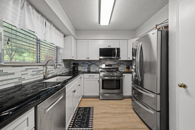 8410 Glen Canyon Dr, Round Rock, TX 78681 - kitchen with appliances with stainless steel finishes, tasteful backsplash, white cabinets, a textured ceiling, and light wood-style flooring