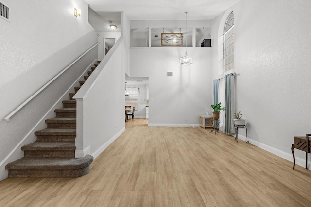 8410 Glen Canyon Dr, Round Rock, TX 78681 - unfurnished living room featuring wood finished floors, stairs, a high ceiling, and healthy amount of natural light