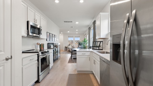 2620 Caleb Asher Loop, Round Rock, TX 78665 - kitchen with stainless steel appliances, white cabinets, light wood-style floors, recessed lighting, and light countertops