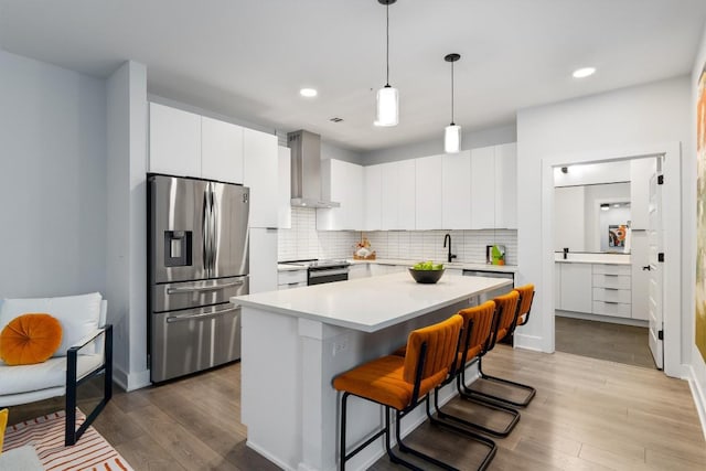 2220 Webberville Rd Unit 207, Austin, TX 78702 - kitchen with stainless steel fridge, wall chimney exhaust hood, light countertops, wood finished floors, and a kitchen bar