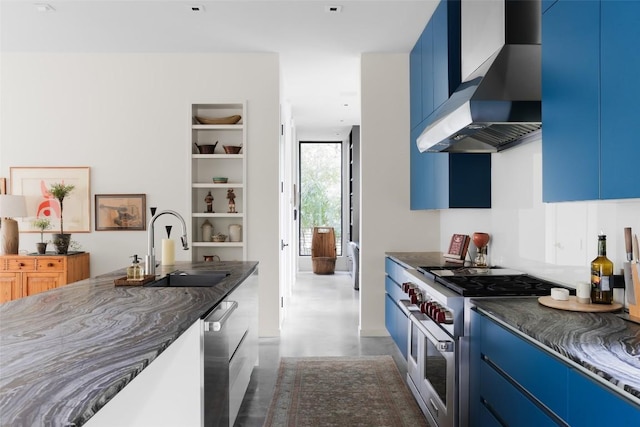 2700 Stratford Dr, Austin, TX 78746 - kitchen featuring wall chimney range hood, blue cabinetry, appliances with stainless steel finishes, a sink, and finished concrete flooring