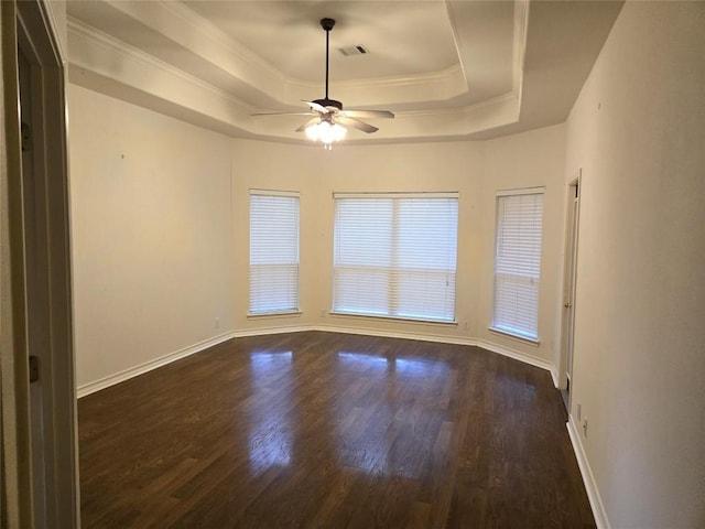 unfurnished room featuring a raised ceiling, ceiling fan, dark wood-style floors, baseboards, and ornamental molding
