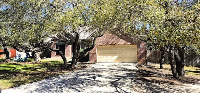 view of side of home with driveway, brick siding, and fence